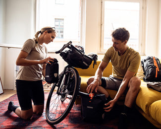 Two people mounting bike bags to a bike